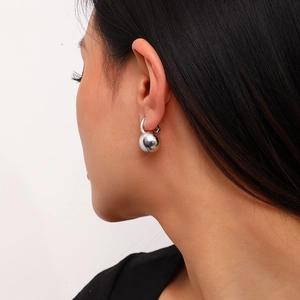 Silver matte brushed spherical ball hoop earrings worn by a model in a side profile view