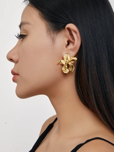 Detail of 18K gold-plated irregular flower stud earring on a model ear with metallic texture