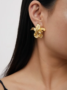 Macro detail of 18K gold-plated irregular floral stud earring with textured metal petals