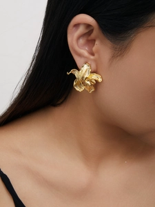 Detailed close-up of a 18K gold-plated irregular flower earring on a female model