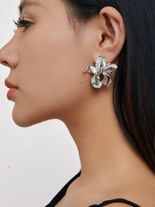 Detailed close-up of a large silver irregular flower stud earring on a female model
