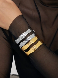 Detail of 18K gold and silver open cuff bracelets with hammer texture on model wrist