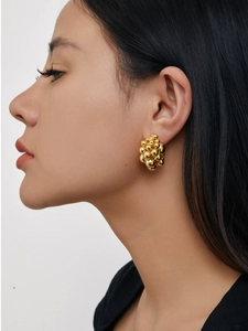 Macro detail of high-polish 18K gold cluster ball earrings on model ear lobe