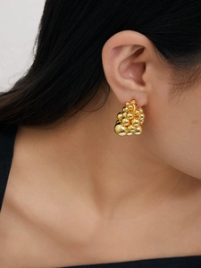 Macro detail of 18K gold clustered metal ball earrings with grape-like stacked design