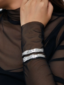 Macro detail of silver open cuff bracelet with irregular hammered metal texture and ripples