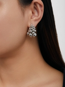 Detailed view of silver metallic grape cluster ball earrings on a female model