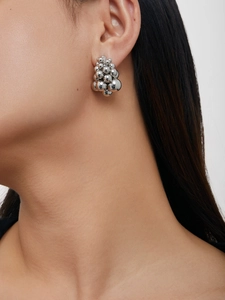 Detail of silver clustered metal ball earrings with grape drop design on a female model