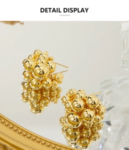 Macro detail of 18K gold clustered metal spheres on C-shaped earrings with mirror reflection