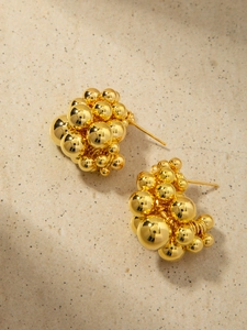 Detailed macro view of 18K gold cluster bead earrings with high-shine metallic texture