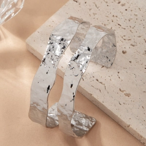 Silver hammered texture open bangles with irregular edges on decorative stone display