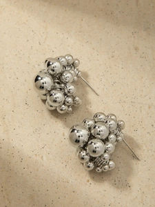 Macro view of silver cluster bead earrings with polished metallic globes on stone