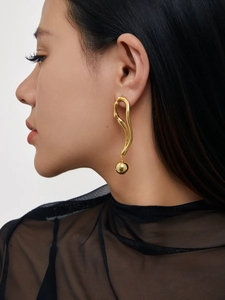 Détail des boucles d'oreilles plaquées or 18 carats à courbe irrégulière avec boule en métal