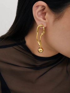 Gros plan de la boucle d'oreille géométrique en or 18 carats avec pendentif boule en métal