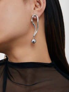 Détail de boucles d'oreilles argentées courbées avec pendentif boule sur modèle