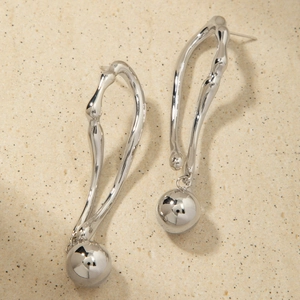 Détail macro de boucles d'oreilles argentées incurvées avec pendentifs sphères en métal