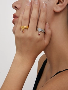 Detailaufnahme von Lava-Struktur Ringen in Gold und Silber mit roten Edelstein-Anhängern