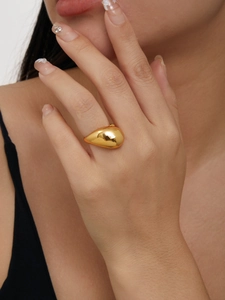 Bague goutte d'eau dorée avec finition miroir portée par un mannequin, look élégant
