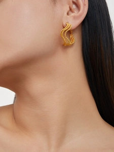 Detail showing multi-layer gold beaded earrings with wavy texture on a female model
