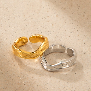 Dettaglio di anelli in oro 18K e argento con texture a onde irregolari e fascia regolabile