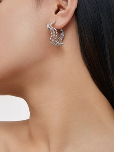 Macro shot of silver multi-row wavy beaded hoop earrings worn by a female model