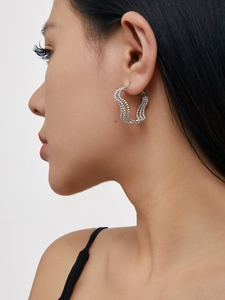 Detail view of silver triple-layered beaded wave earrings on a model's ear
