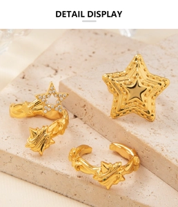 Détail de trois bagues étoiles dorées 18K ornées de zircons sur support en pierre