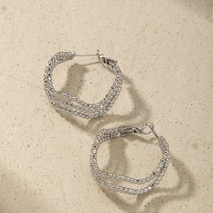Detailed macro view of silver multi-layer beaded hoop earrings with a textured metal finish