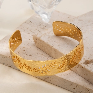 Detail of 18K gold-plated cuff bracelet featuring a hammered texture and cutout leaf pattern