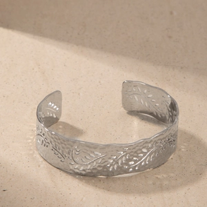 Macro detail of silver hammered texture and engraved leaf vine pattern on open cuff bangle