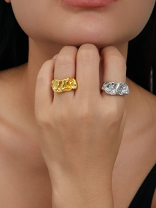 Detail of gold and silver irregular lava rings with a crumpled texture on a model hand