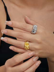 Close-up of stacked gold and silver lava rings with irregular fluid texture on model
