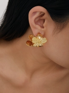 Détail macro de boucles d'oreilles fleur plaquées or 18K avec pétales texturés et relief