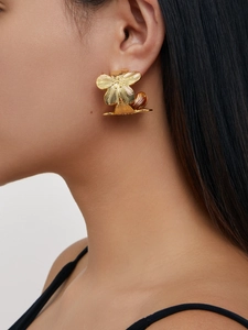 Détail de grandes boucles d'oreilles fleur en or 18 carats avec texture brossée