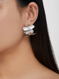 Détail d'une grande boucle d'oreille fleur argentée multicouche à texture radiale