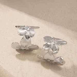Vue détaillée de boucles d'oreilles fleurs argentées avec texture de pétales ciselés