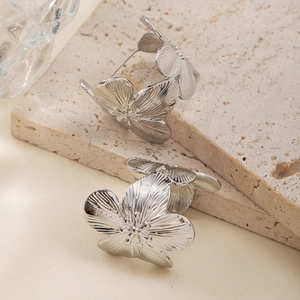 Détail de boucles d'oreilles fleurs argentées avec pétales 3D et textures fines