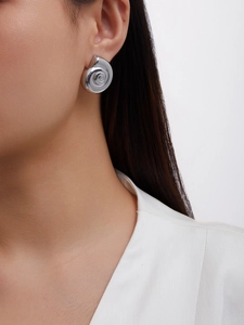 Detailed close-up of a silver spiral conch earring in a minimalist seashell design