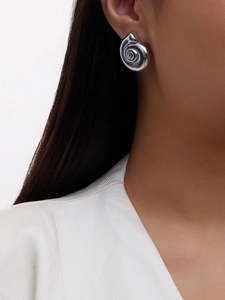 Close-up of a silver spiral shell earring featuring a polished metallic mirror finish