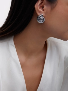 Detail view of a silver spiral conch earring worn by a model on a white background