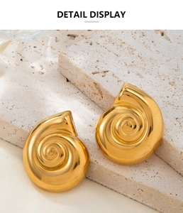 Detail display of 18K gold-plated conch shell earrings on a textured stone surface