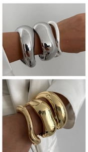 Detailed macro view of chunky polished gold and silver alloy cuff bracelets with mirror finish