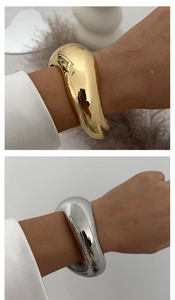 Macro detail of minimalist chunky irregular geometric alloy bangle in gold and silver