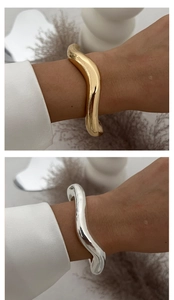 Detail showing polished gold and silver metal bangles with irregular wavy organic design