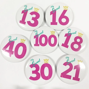 Vue à plat de badges d'anniversaire en fer-blanc avec divers âges et motifs royaux