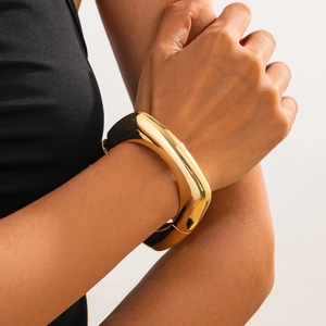 Chunky gold-plated geometric metal bangle with a polished finish and hinge closure