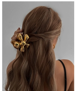Detail of a golden alloy flower hair claw clip with a polished finish on a model's hair