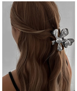 Detail of silver metallic flower hair claw clip on brunette wavy hair for elegant styling