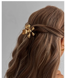 Detail of a golden flower-shaped hair claw clip on a woman's hair with polished finish