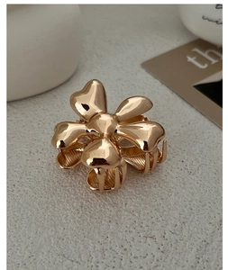 Detailed macro shot of a golden alloy flower hair claw with a polished mirror finish