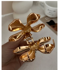 Macro detail of glossy golden flower hair claw clip with intricate engraved textures